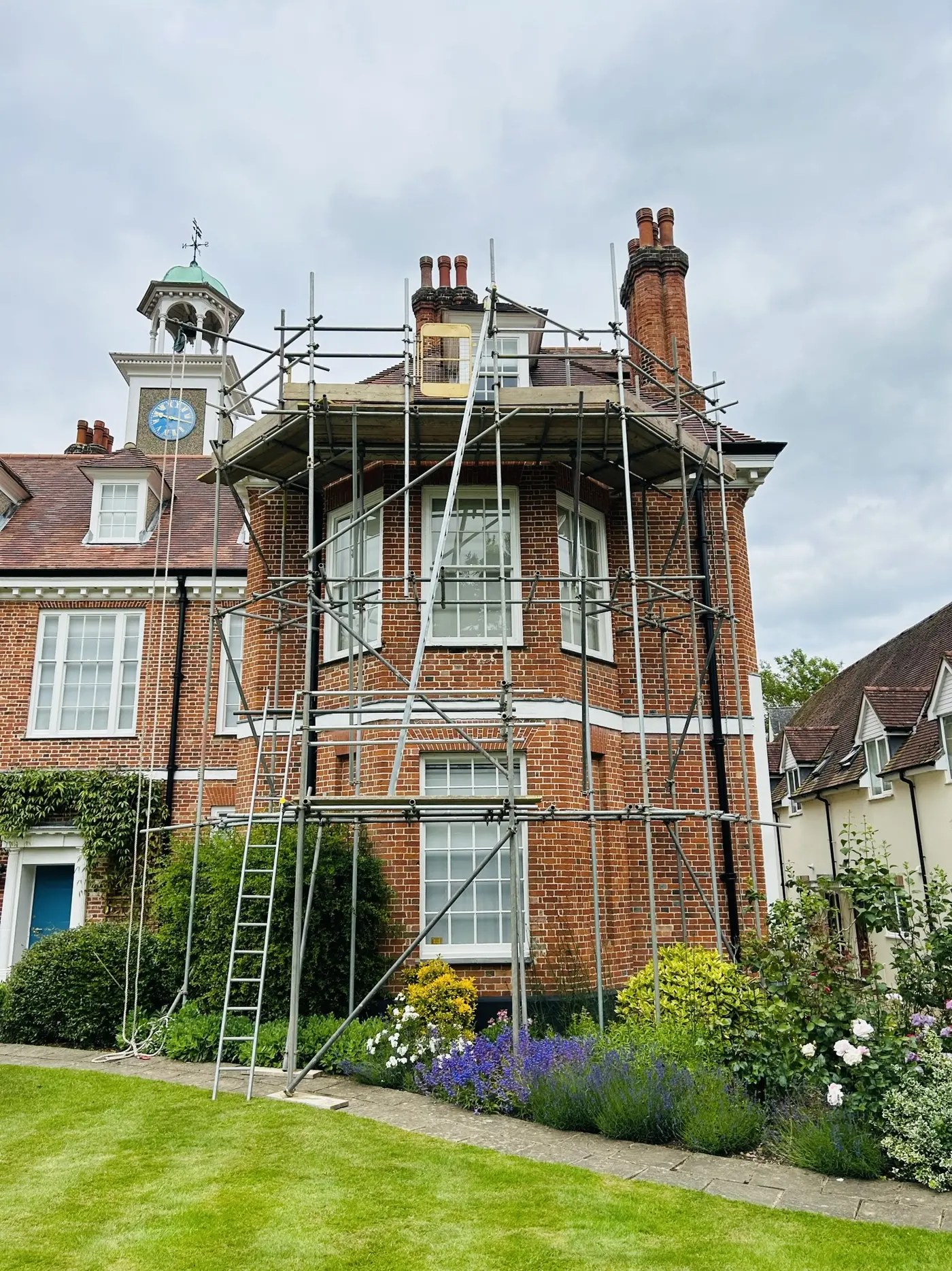 Scaffolding around the bay and roofline of a period red-brick building
